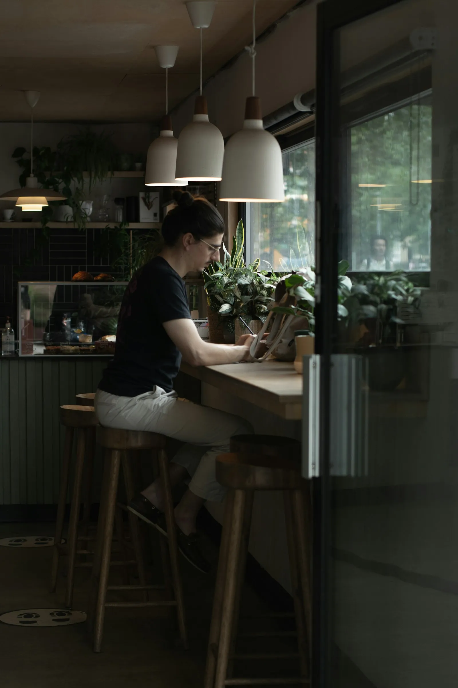 A man working on a laptop at a window counter in a small cafe