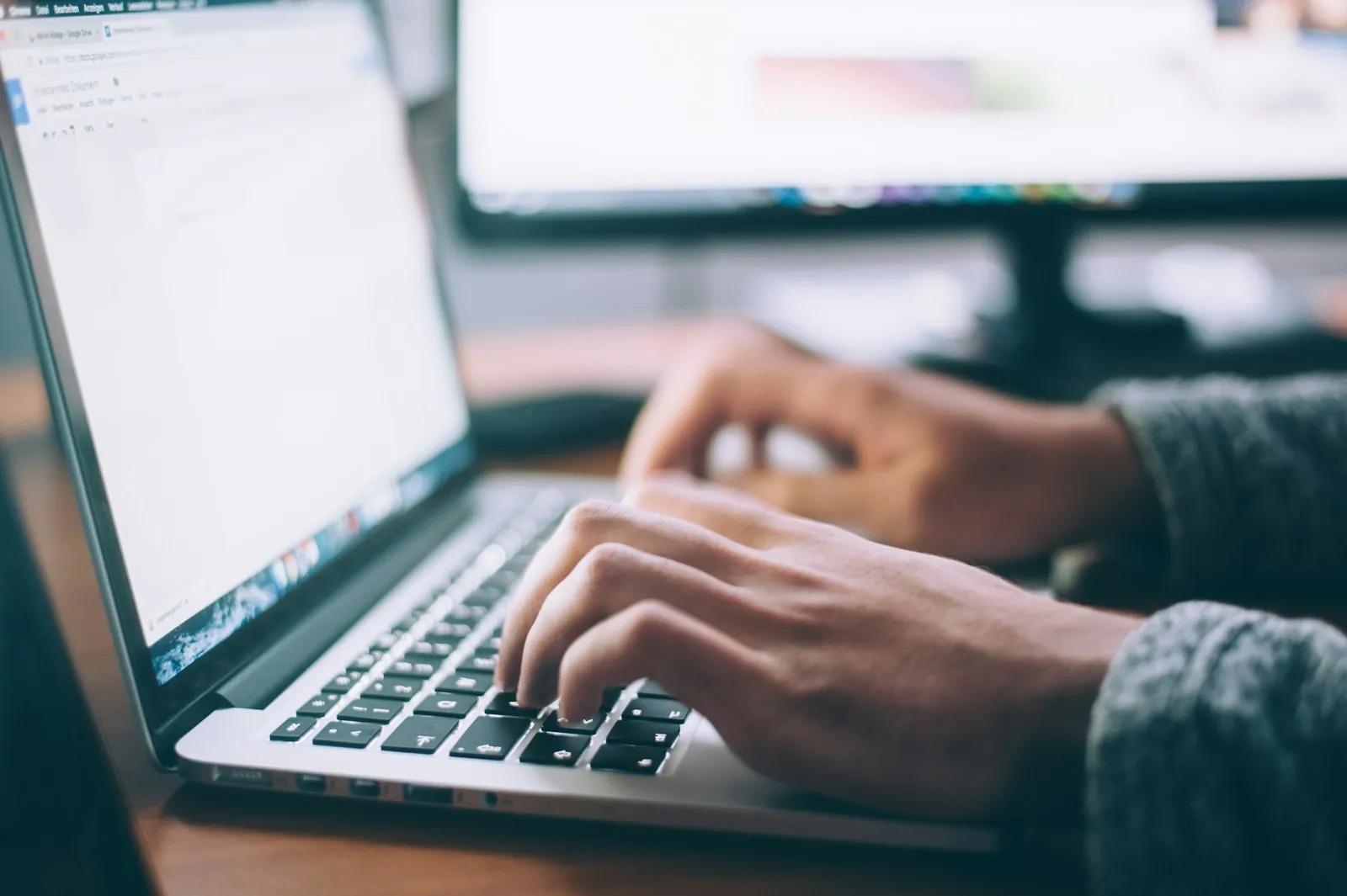 A person writing an email on a laptop at a desk